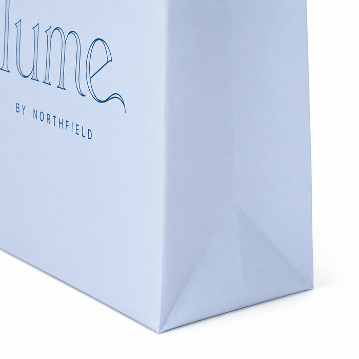 Side close-up of light blue branded paper bag with folded triangle base and serif logo print