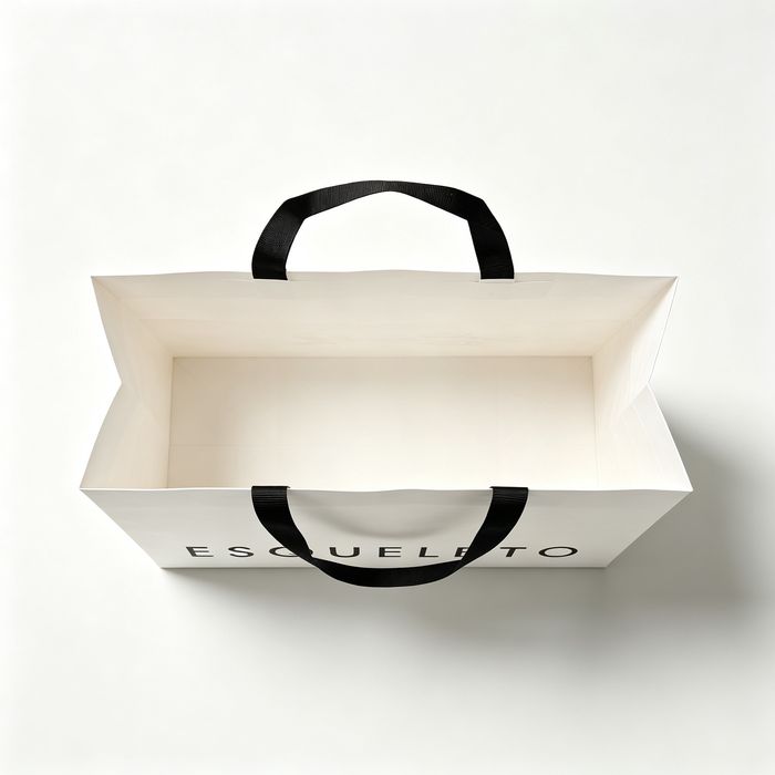 Top-down shot showing the wide interior of an empty white paper sack with black fabric handles.