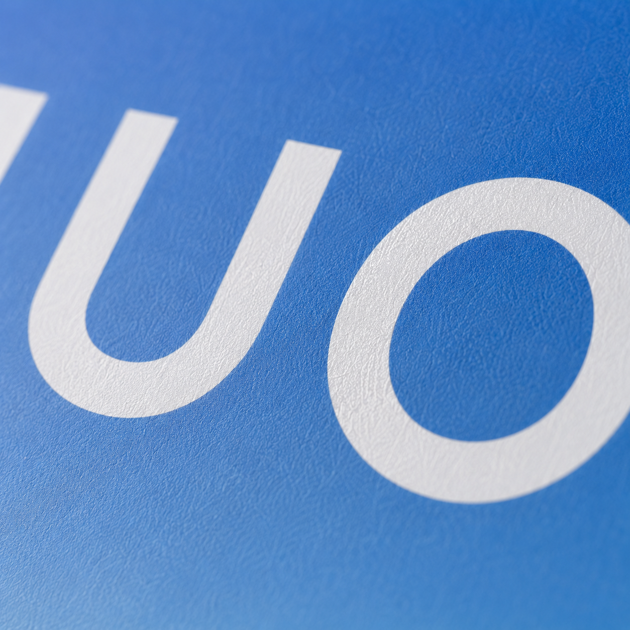 Ultra close-up shot showcasing matte paper texture and sharp TUOBO logo printing on blue gradient shopping bag surface
