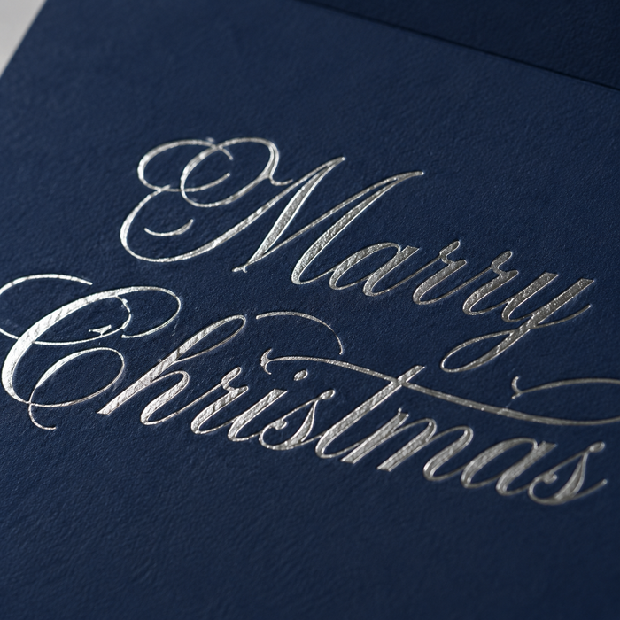 Close-up of navy blue custom Christmas gift box with silver foil embossed “Merry Christmas” typography, premium textured surface, luxury holiday packaging for retail and B2B wholesale branding.