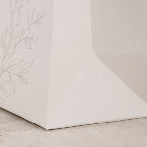 Macro close up capturing folded bottom seam and natural paper grain texture of custom printed luxury paper shopping bag