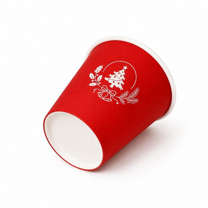 Close-up tilted shot of red Christmas paper cups with custom Christmas tree logo, recyclable eco friendly Christmas disposable cups, printed seasonal holiday paper cups wholesale from professional Christmas cups supplier