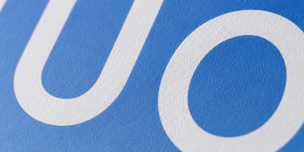 Ultra close-up shot showcasing matte paper texture and sharp TUOBO logo printing on blue gradient shopping bag surface