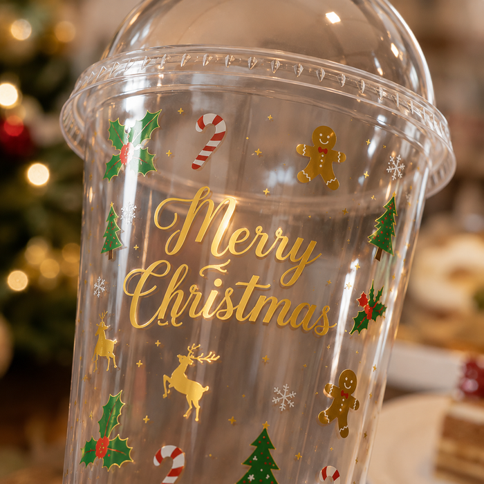 Close up view gold foil Merry Christmas pattern clear plastic cup, gingerbread man candy cane holly tree printed reusable tumbler bulk wholesale for Xmas café supplies