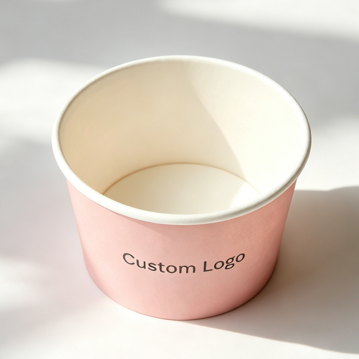 Overhead shot empty pastel pink biodegradable paper ice cream cup with white inner liner, custom logo printable disposable dessert container on plain white background, soft natural light