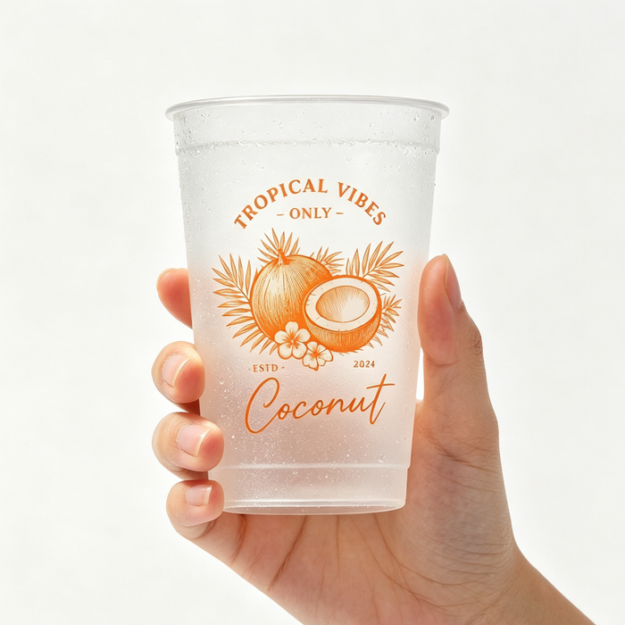 A close-up of a hand holding a custom beverage container with a vibrant orange tropical coconut print, showcasing frosted plastic cups with a sleek matte finish drink cups appearance.